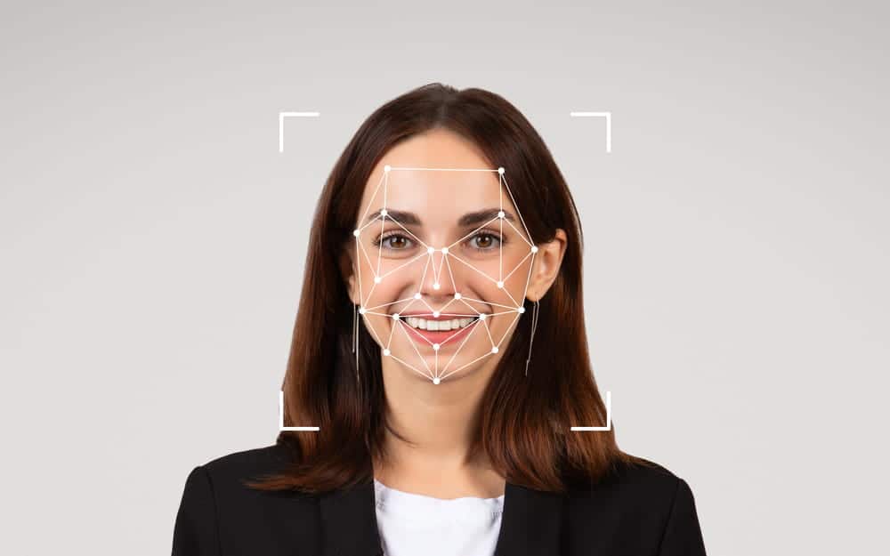 Image is of a woman with facial mapping technology applied, showing AI image abuse risks related to biometric data use and lack of consent