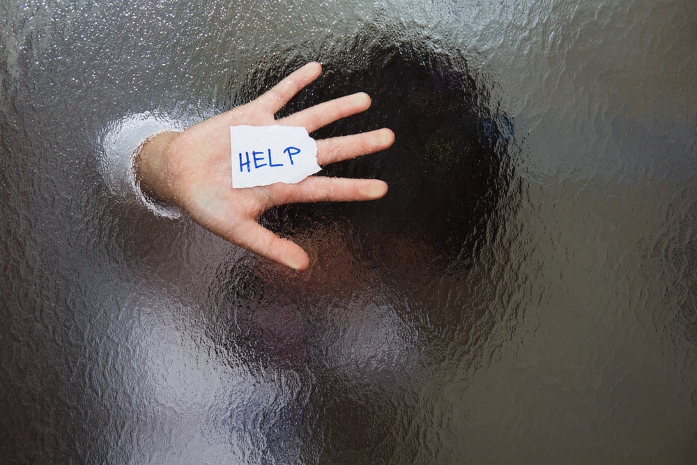 Image is of a hand pressed against frosted glass holding a help sign, representing sexual assault survivors seeking protection and legal options.