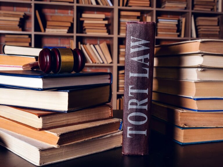 Image is of stacked law books with a gavel in a legal library, concept of research and statutory requirements for a mass tort claim in Louisville
