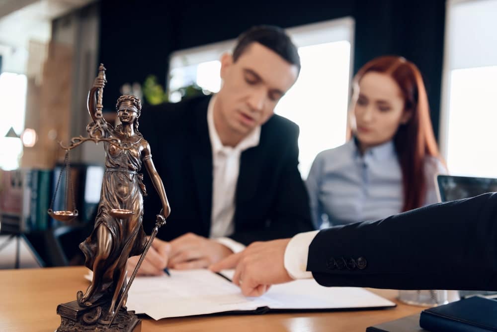 Image is of two lawyers reviewing legal documents together at a desk, concept of evaluating evidence and qualifications for a mass tort claim in Louisville.