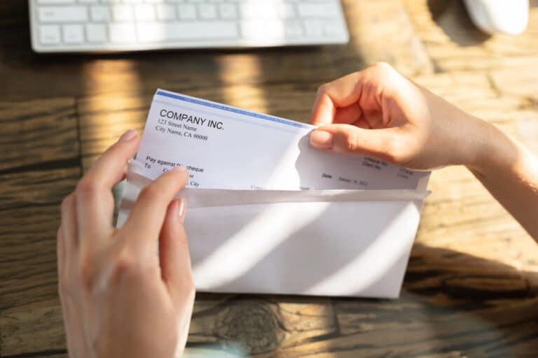 Image is of a person opening a paycheck envelope, illustrating wage protection and payment rights under labor law for workers.