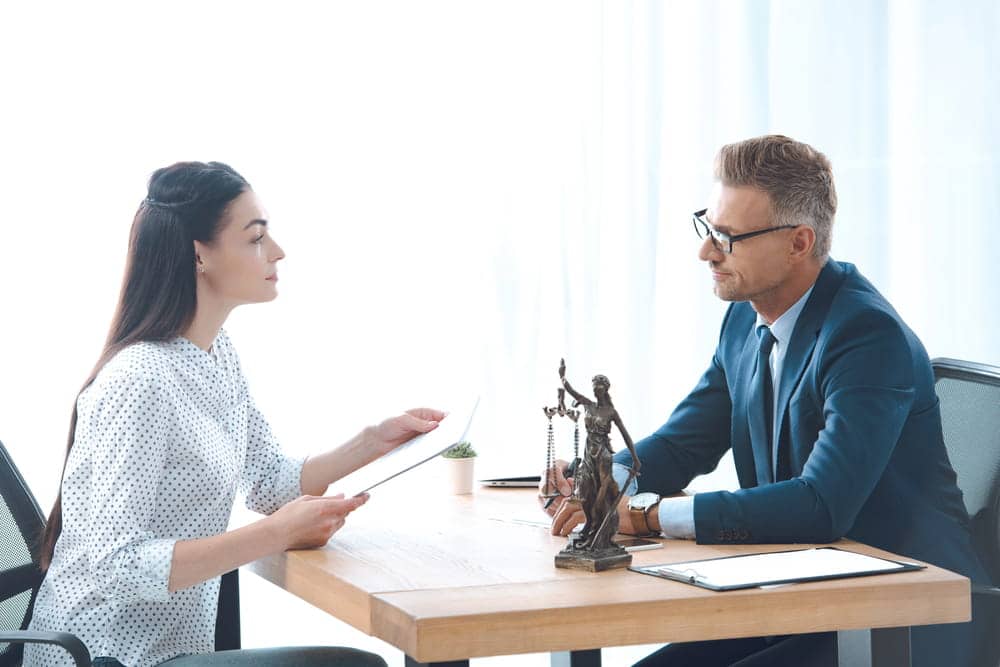 Image is of a lawyer consulting with a client at a desk, concept of class actions and legal guidance