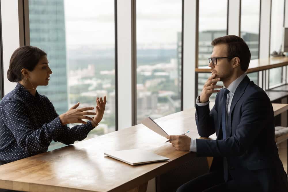 Image is of a professional consultation between an employee and HR manager in a modern office setting, concept of labor law protections and workplace rights discussions.
