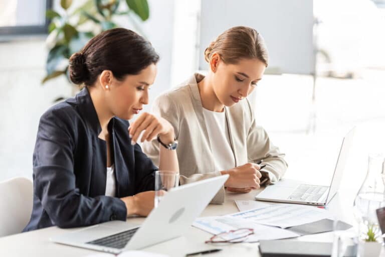 Image is of two professionals reviewing employment paperwork on a laptop and documents, concept of labor law compliance and employee rights evaluation.