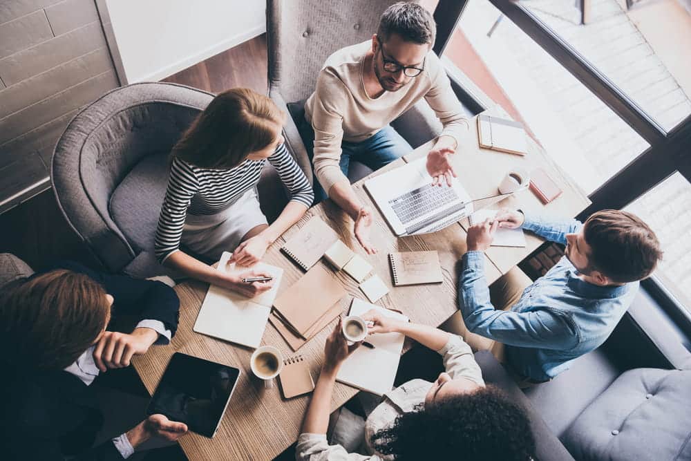 Image is of coworkers gathered around a table during a workplace discussion, showing how union workers collaborate and advocate for fair labor rights.