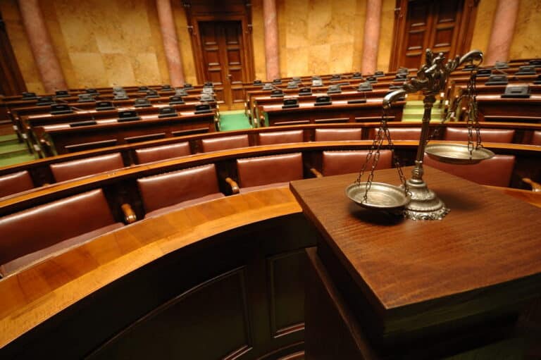 Image is of a courtroom with scales of justice in the foreground, representing the legal process involved in a mass tort lawsuit in Nashville.