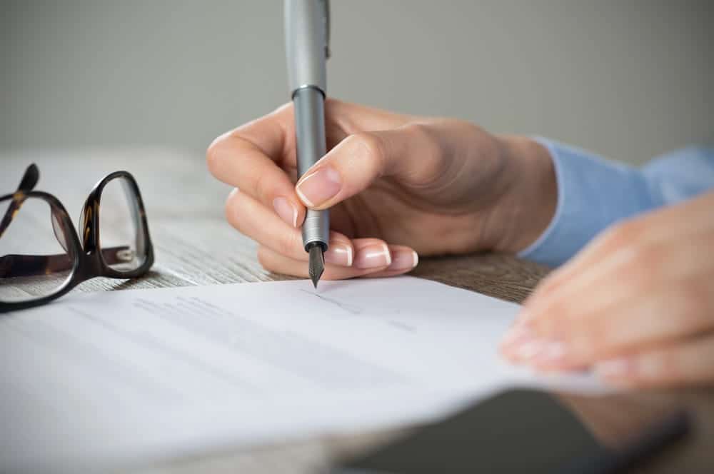 Image is of a person signing legal paperwork, illustrating documentation requirements for joining a mass tort lawsuit.
