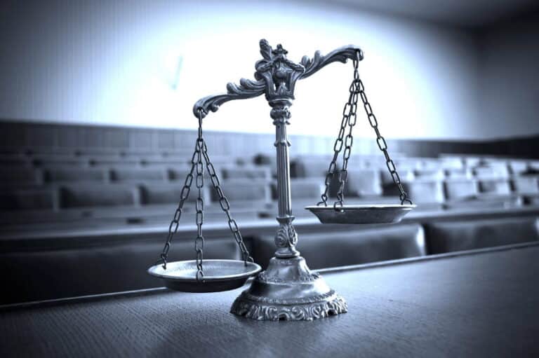 Image is of scales of justice placed inside a courtroom setting, representing civil litigation in Washington