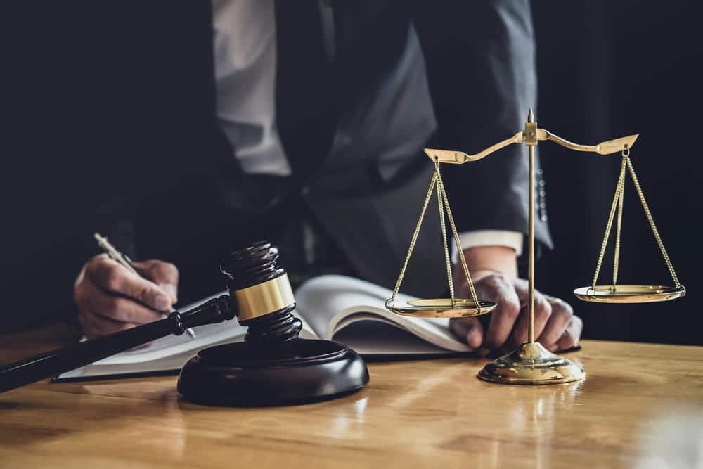 Image is of a lawyer reviewing legal documents beside a gavel and scales of justice, representing civil litigation in Washington