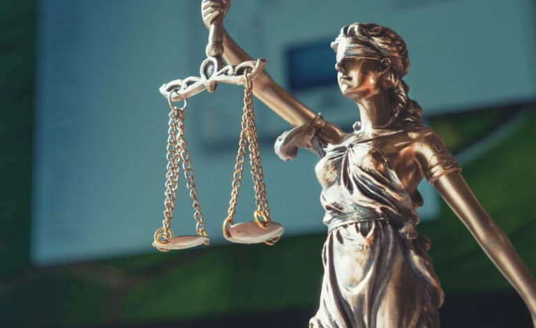 Image is of Lady Justice holding scales, representing fairness and legal balance in litigation in Kentucky