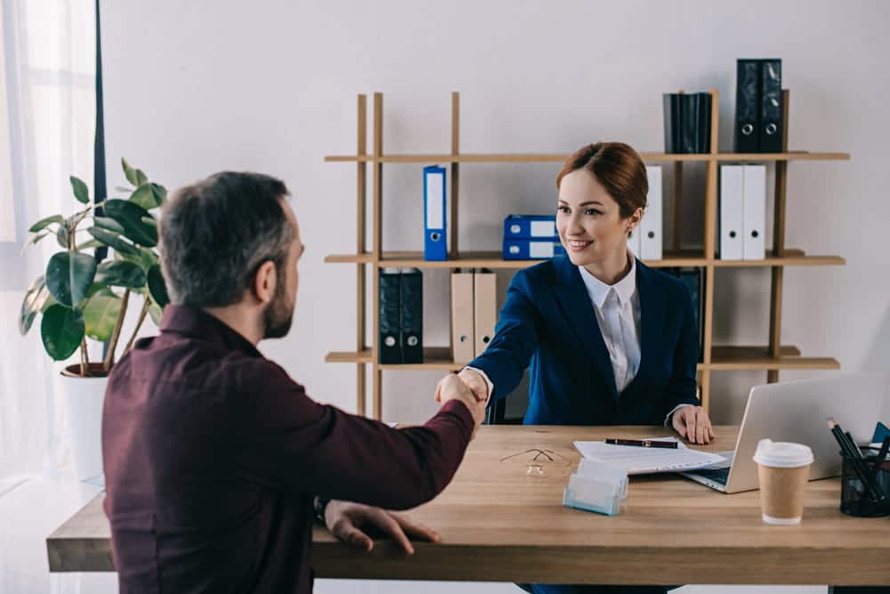 Image is of a lawyer shaking hands with a client in an office setting, reflecting civil litigation and legal consultation
