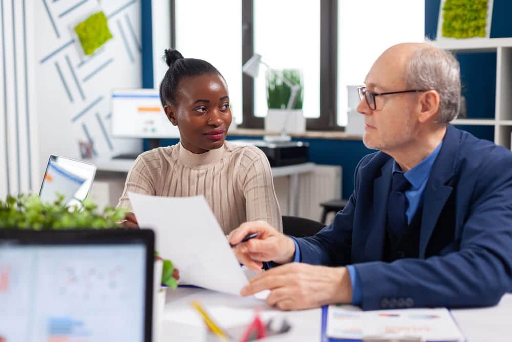 Image is of two professionals examining paperwork during a workplace meeting, illustrating the duty of fair representation when unions review employee grievances.