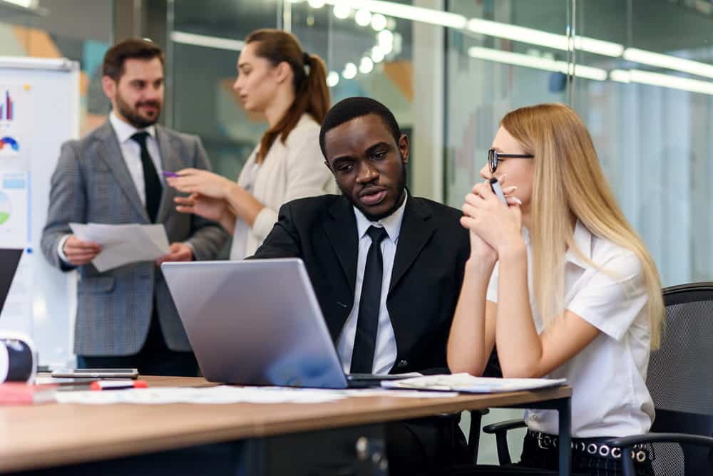 Image is of office colleagues reviewing documents and discussing a workplace grievance on a laptop, concept of duty of fair representation in a union workplace dispute.
