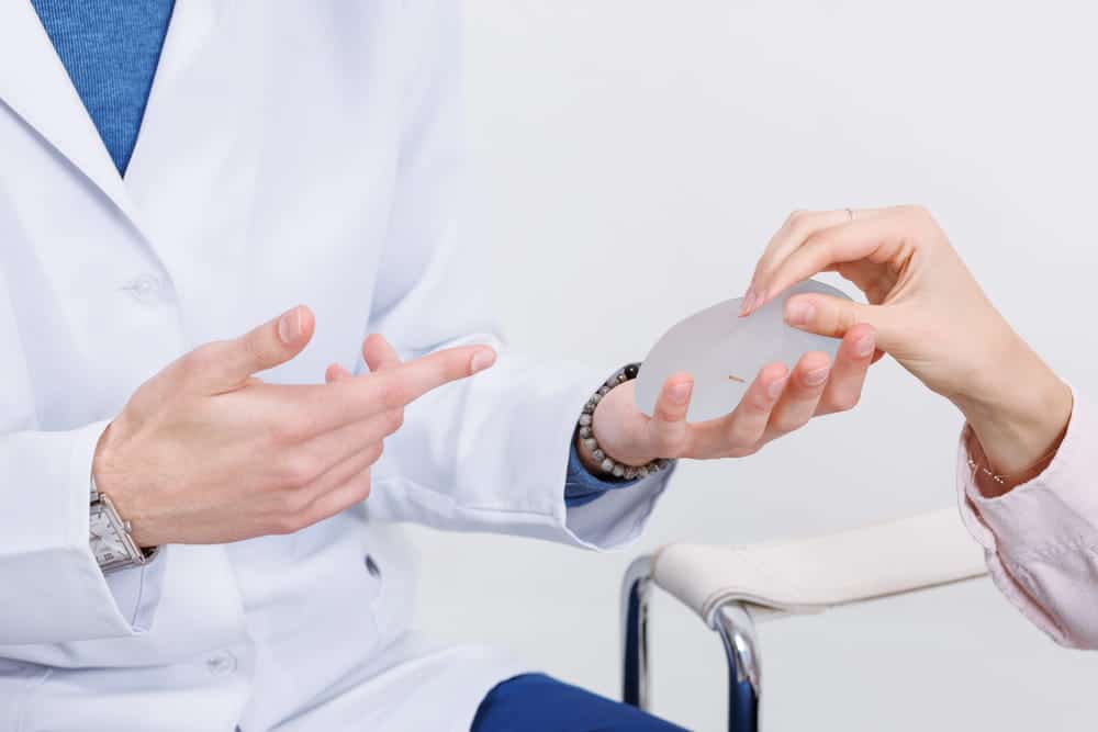 Image is of a close-up breast implant being examined by a doctor, concept of breast mesh used in reconstructive procedures