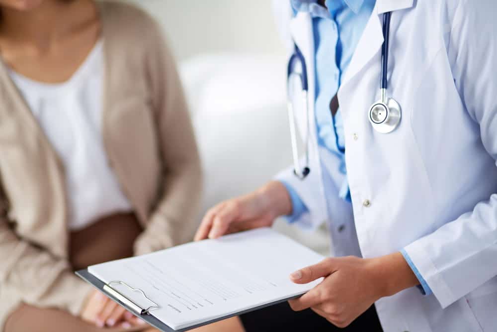 Image is of a doctor explaining to a patient, concept of diagnosing complications related to breast mesh failure