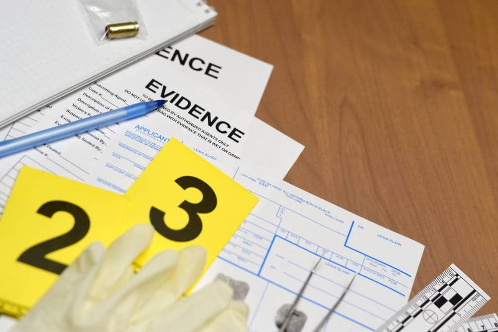 Image is of evidence markers, gloves, and documentation forms on a desk, showing how physical evidence is collected and documented in sexual assault claims