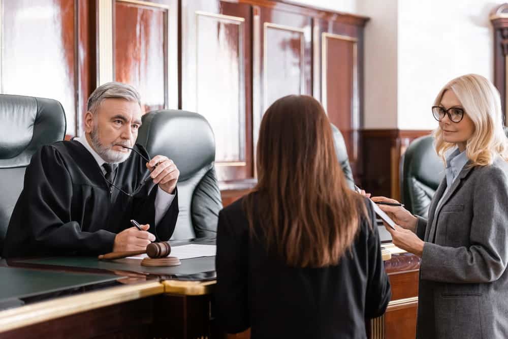 Image is of attorneys and a judge discussing legal matters inside a courtroom, concept of mass tort litigation in Washington, D.C.