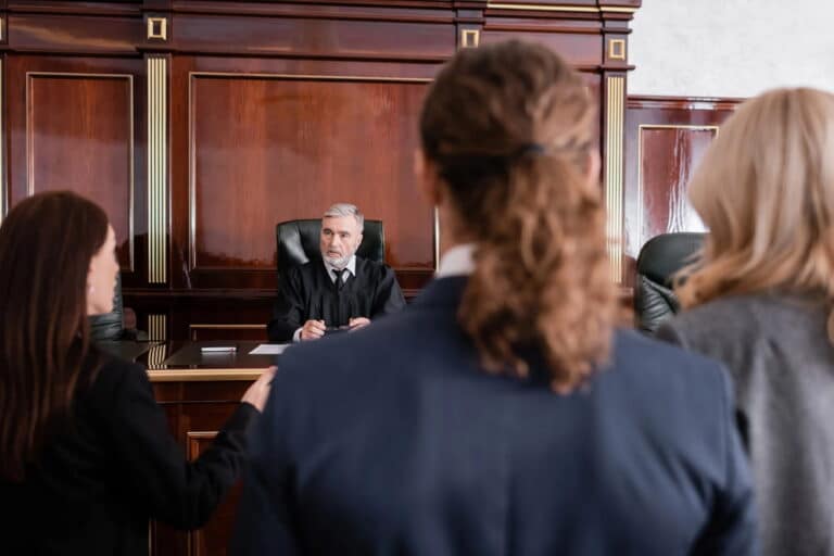 Image is of attorneys and clients standing before a judge during courtroom proceedings, concept of a mass tort trial hearing in Washington, D.C.