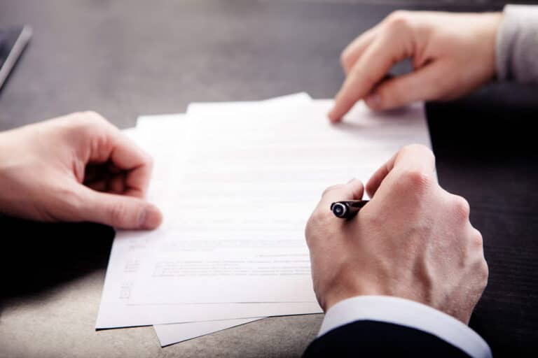 Image is of two individuals reviewing and signing paperwork together, concept of labor contract agreements and employment enforcement in Ohio.