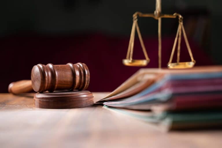 Image is of a courtroom gavel placed beside stacked case files and scales of justice, concept of class actions in Nashville