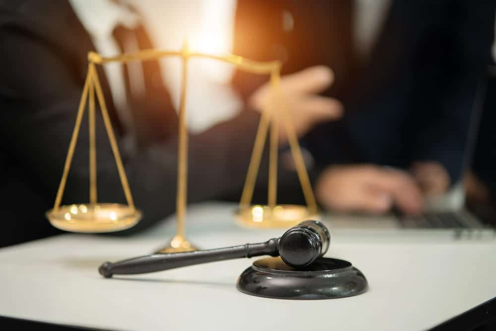 Image is of a gavel and balance scales on a desk during a legal consultation, concept of class actions in Nashville