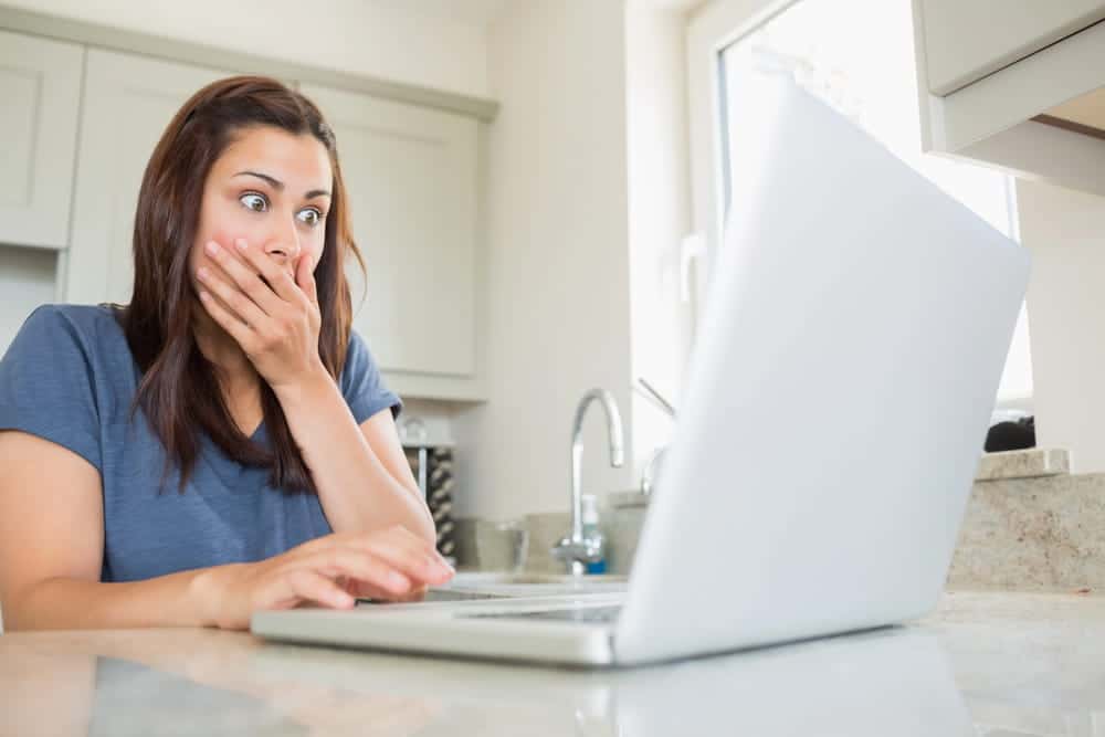 Image is of a person looking at a laptop with a shocked expression, representing the emotional impact of AI-altered images on personal rights.