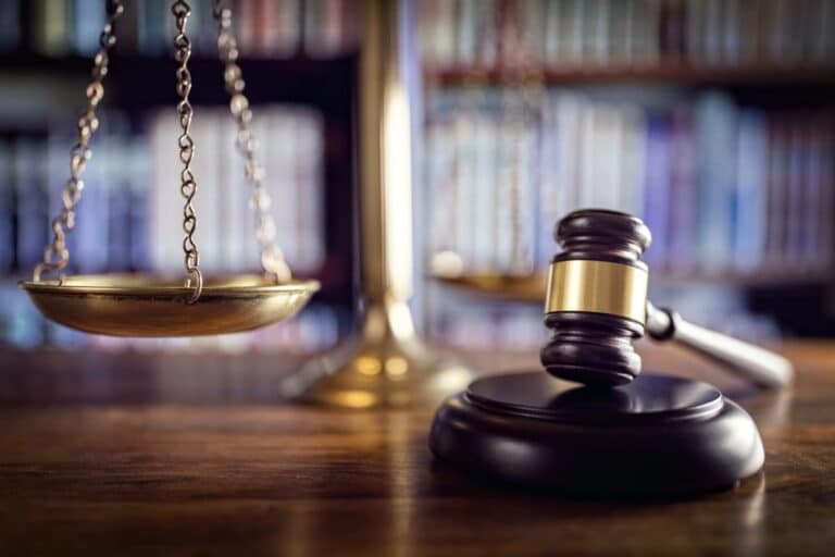 Image is of a judge's gavel and scales of justice in a courtroom setting, concept of the legal process involved in litigation in Tennessee.