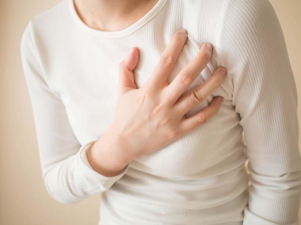 Image is of a person holding their chest after breast surgery, concept of surgical mesh complications causing pain and discomfort.