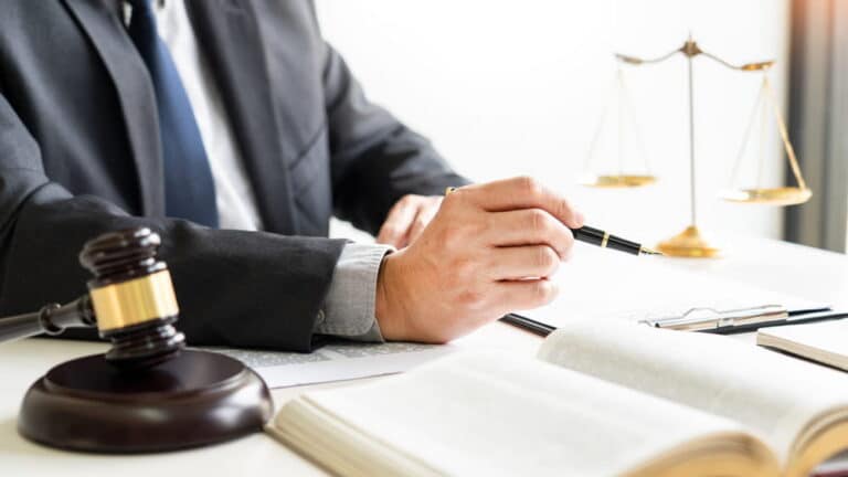 Image is of an attorney reviewing legal documents at a desk with a gavel and scales of justice in the background, concept of summary judgment in Washington, D.C.