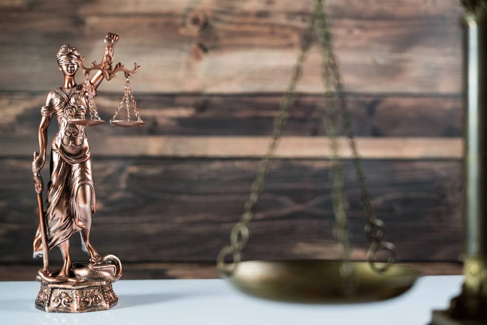 Image is of a Lady Justice statue displayed beside scales of justice, concept of a civil case and the legal process that may lead to trial in Cincinnati courts.