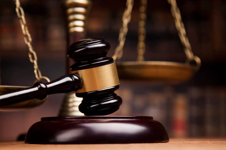 Image is of a judge's gavel with scales of justice in the background, concept of court proceedings involving defective breast mesh.