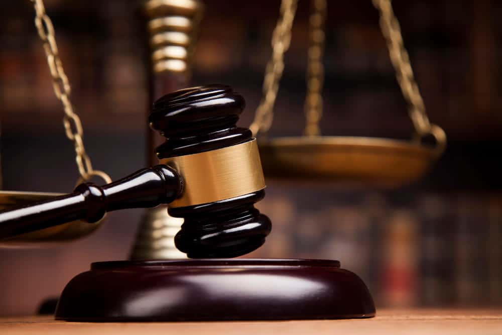 Image is of a judge's gavel with scales of justice in the background, concept of court proceedings involving defective breast mesh.