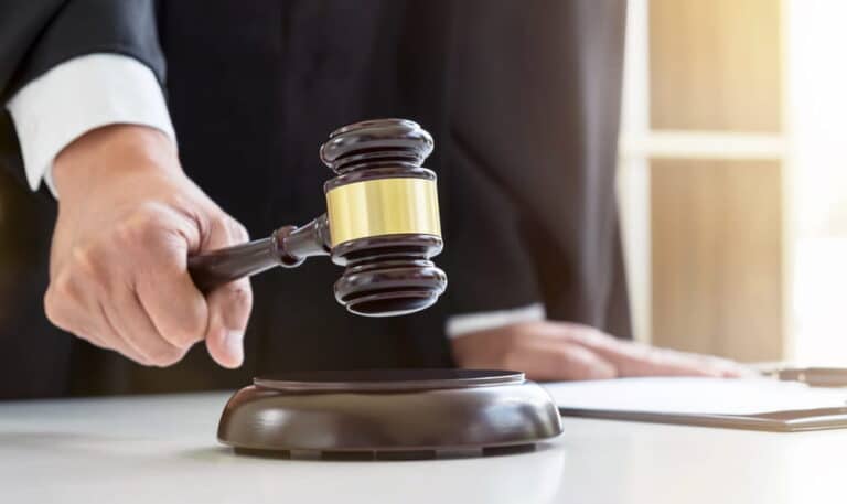 Image is of a judge holding a gavel in a courtroom setting, concept of sexual assault lawsuits and the legal process.