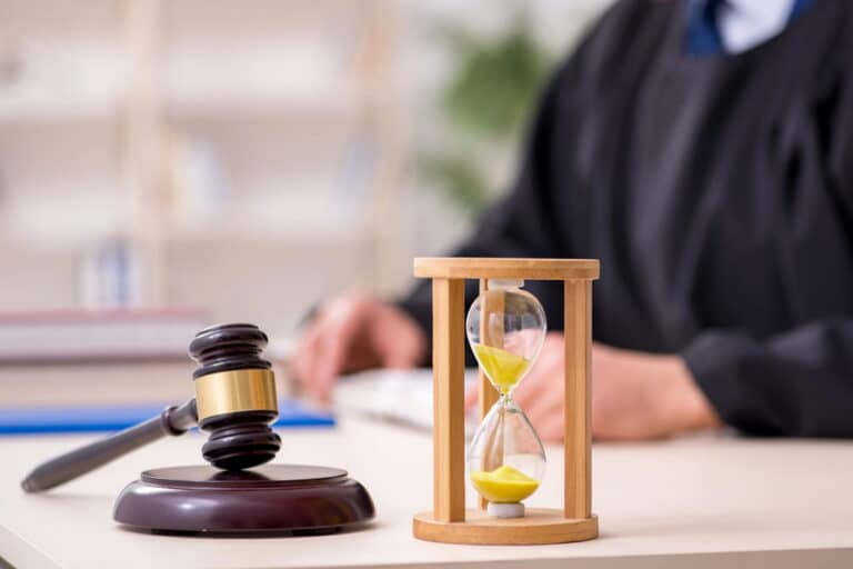 Image is of a judge's gavel and hourglass in front of a judge's bench, concept of mass tort case