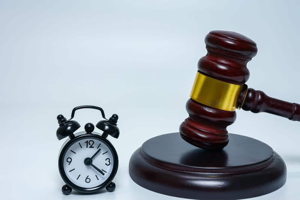 Image is of a judge's gavel placed beside a clock, concept of mass tort case