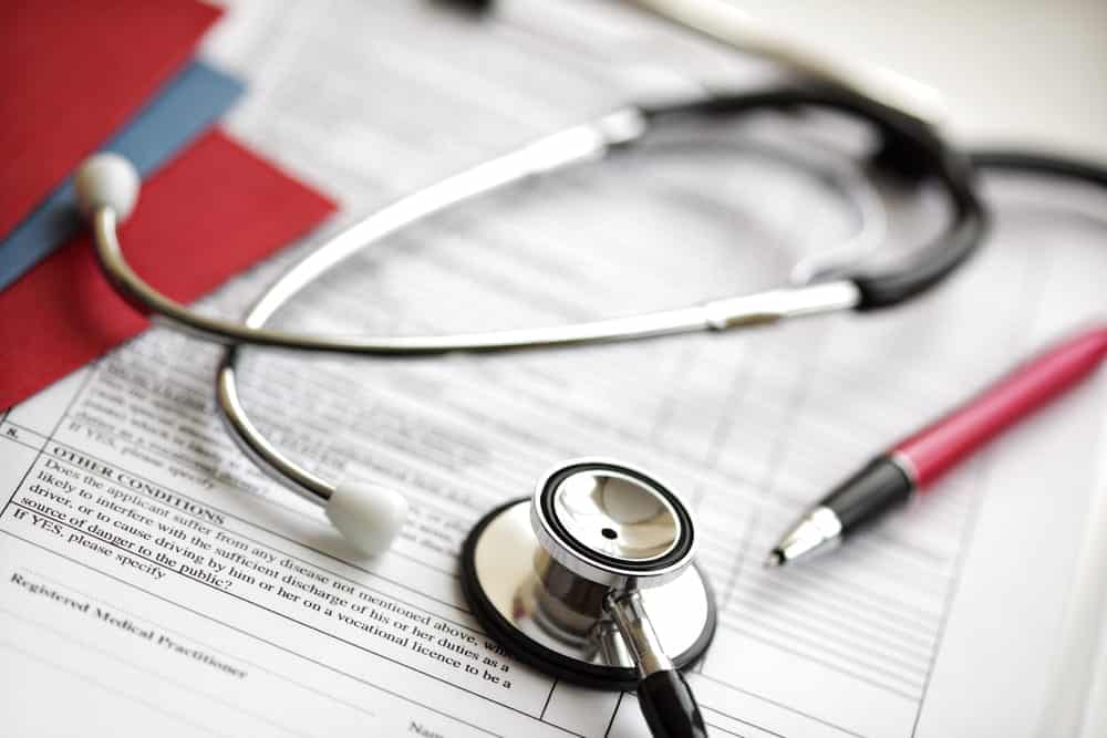 Image is of a stethoscope resting on medical records and documents, concept of mass tort case