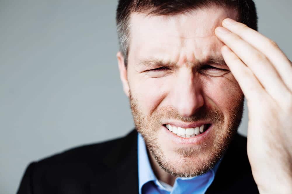 Image is of a man experiencing severe head pain, concept of neurological injuries involved in mass torts in Louisville.