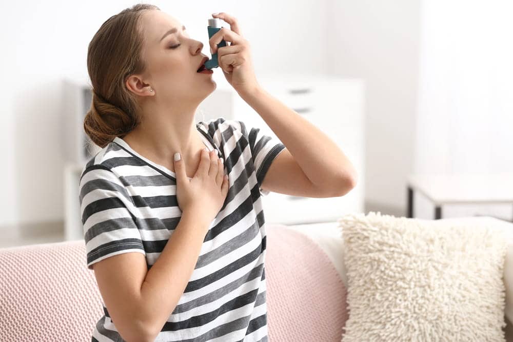 Image is of a woman using an inhaler, concept of respiratory injuries linked to mass torts in Louisville.