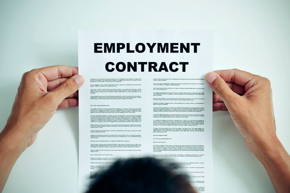 Image is of a person reviewing an employment contract, concept of understanding and enforcing labor contracts in Kentucky