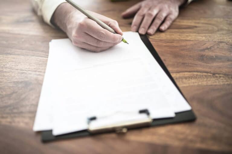 Image is of a person signing a workplace agreement, concept of enforcing labor contracts in Kentucky