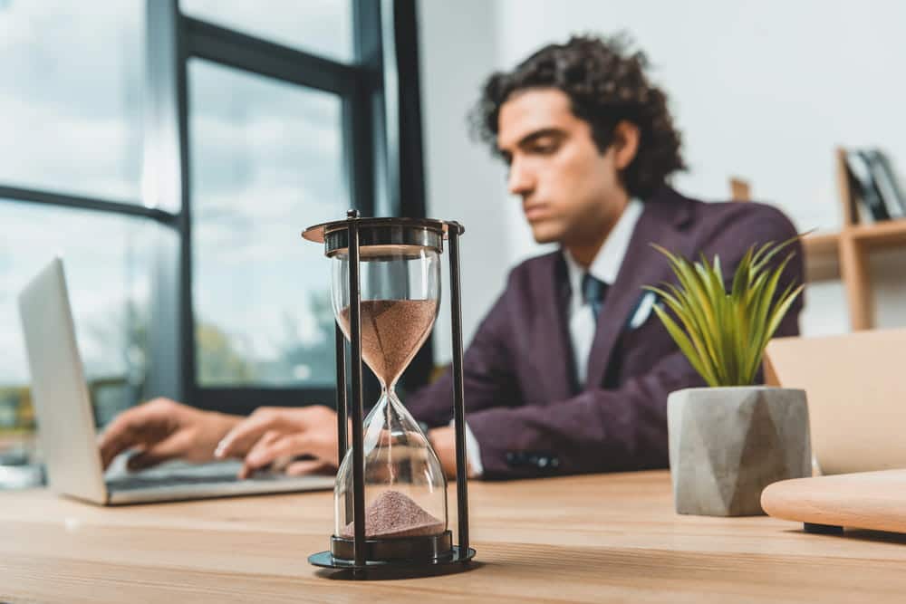 Image is of an employee working beside an hourglass, concept of timing and evidence in a retaliation claim.