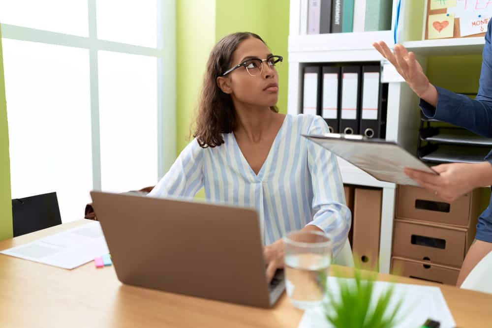 Image is of an employee listening to a supervisor holding workplace documents, concept of a retaliation claim involving adverse employment action.