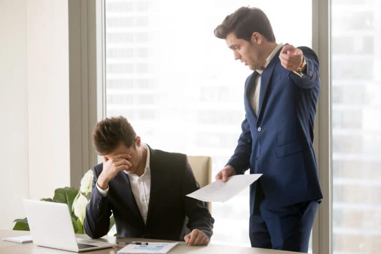 Image is of a distressed employee being confronted by a supervisor with paperwork, concept of a retaliation claim after protected activity.