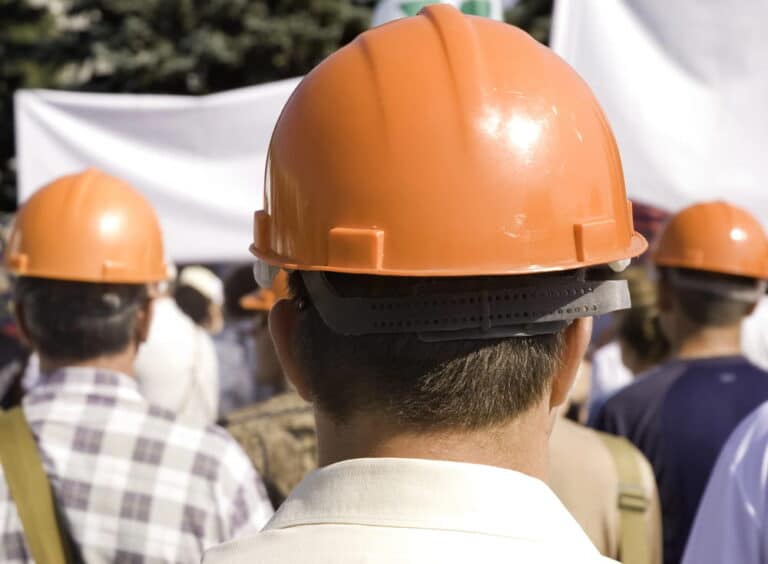 Image is of workers wearing hard hats gathered together, concept of collective workplace rights for union workers.