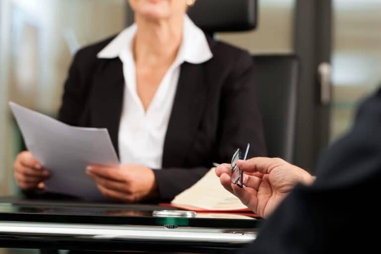 Image is of lawyers and a client reviewing legal documents together, concept of settlement negotiation and case evaluation.