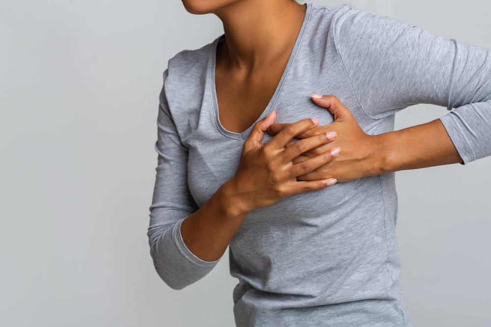 Image is of a woman holding her breast due to pain, concept of possible surgical mesh failure after breast surgery.
