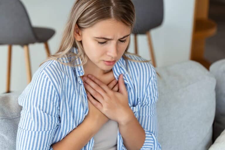 Image is of a woman experiencing discomfort around her chest and breast area, concept of possible surgical mesh failure.