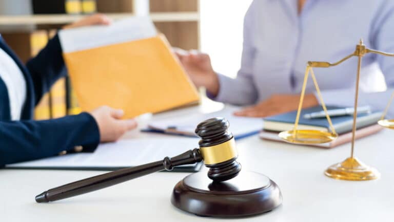 Image is of legal professionals reviewing documents with a gavel and scales, representing evidence review for a sexual assault lawsuit.