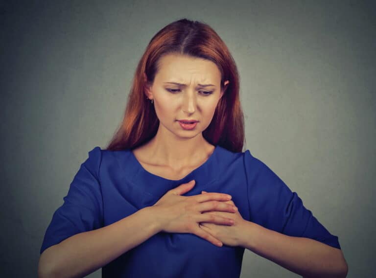 Image is of a woman holding her chest area, representing symptoms and injuries associated with breast mesh in Kentucky