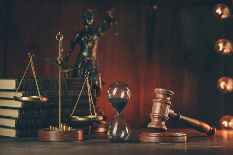 Image is of a judge’s gavel, scales, and hourglass, concept of the filing deadline for a sexual assault claim in D.C.
